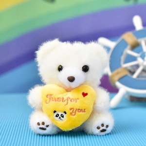Close-up of a cute white teddy bear plush holding a yellow heart with Just for You