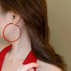 Close-up of model wearing large red hoop earring with a sleek glossy finish