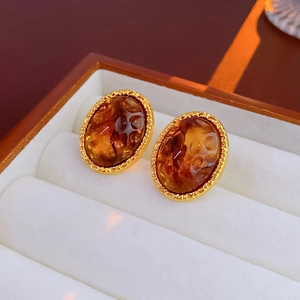 Close-up of irregular brown resin and gold metal earrings on a jewelry box display