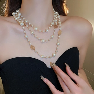 Detail of multi-layer pearl necklace with golden rose charms worn by a model