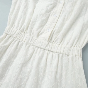 Détail de la robe courte blanche brodée avec patte de boutonnage et taille élastique