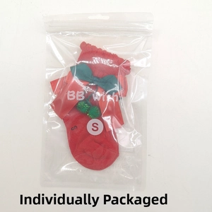 Detail of red Christmas baby socks with green bows in individual plastic packaging