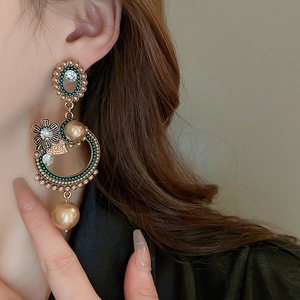 Close-up of vintage floral drop earrings with pearls and crystals on a female model