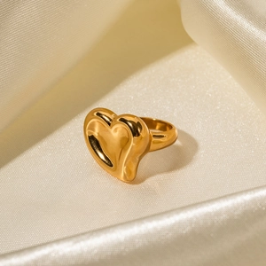 Close-up of 18K gold heart ring on soft beige silk showcasing high-polished finish