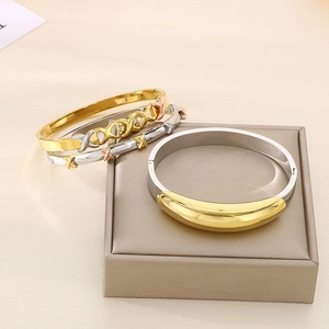 Detailed view of intertwined 18K gold and silver knot bracelets on a display stand