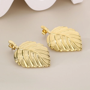Close-up of golden leaf earrings showing detailed natural vein textures and metallic luster