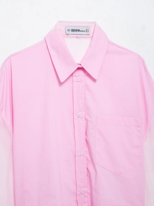 Dettaglio macro del colletto della camicia rosa con cuciture in organza ed etichetta