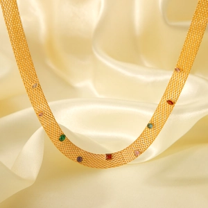 Elegant gold mesh necklace with colorful gemstones on a soft beige silk background