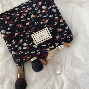 Detailed close-up of textured chiffon cosmetic bag with abstract pebble pattern and makeup items