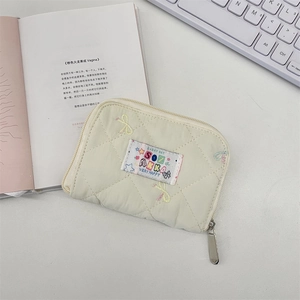 Close-up of quilted cream wallet with cartoon patch and zipper on desk setting
