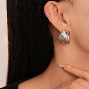 Close-up of model wearing silver spiral shell-textured geometric stud earrings