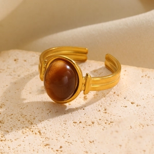 Detail of vintage gold ring featuring a large oval tiger eye stone on a textured stone