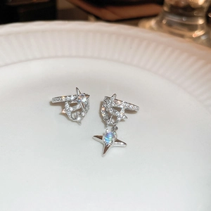 Macro shot of silver asymmetric star ear cuff with zircon and moonstone on ceramic