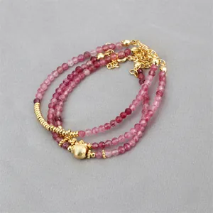 Detailed macro view of triple-layered red carnelian beaded bracelet with gold plated beads