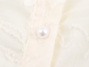 Close-up of pearl button and textured jacquard fabric on a French style blouse