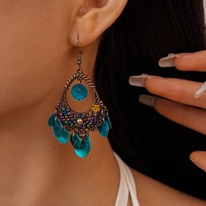 Macro side view of Bohemian bronze drop earrings with colorful beads and blue shell pendants