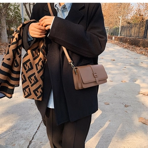 Brown leather square crossbody bag shown in a stylish outdoor street style autumn setting