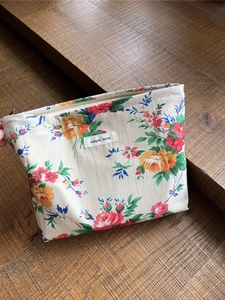 Detailaufnahme der floralen Baumwoll-Kosmetiktasche mit Reißverschluss und Etikett