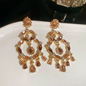 Detail of luxury water drop earrings with amber crystals and grey pearls on gold finish