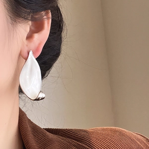 Close-up of a white irregular teardrop earring worn by a model with a minimalist design