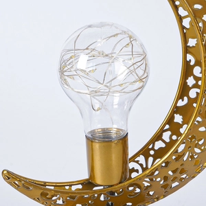 Gros plan sur une lampe lune dorée en fer avec ampoule en verre et guirlande LED
