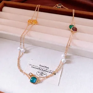 Vintage gold long necklace with colorful square gemstones and white pearls on velvet