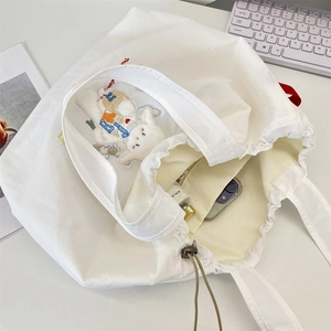 Detailed interior of a white canvas tote bag with sheep embroidery and drawstring closure