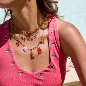 Detailed view of layered gold titanium necklace with cherry and bear pendants on model