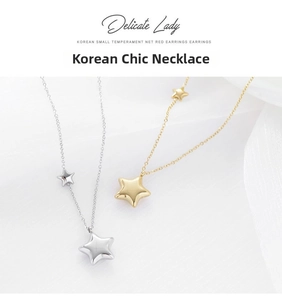 Detail of double star pendant necklaces in polished gold and silver on white fabric