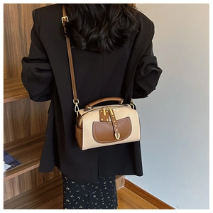 Vue détaillée du sac à bandoulière en cuir beige et marron porté par un mannequin