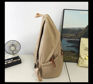 Detail view of khaki canvas backpack side pocket with adjustable strap and leather pulls