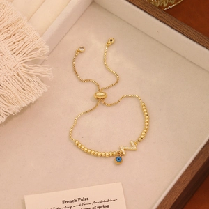 Dettaglio del bracciale a sfere dorate con ciondolo lettera Z e amuleto malocchio blu