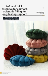 Close-up of shell-shaped velvet pillows in multiple colors stacked on a white rug