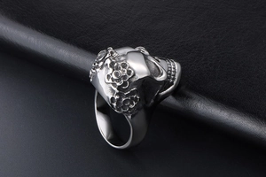 Macro shot of silver skull ring with floral embossing on dark leather background