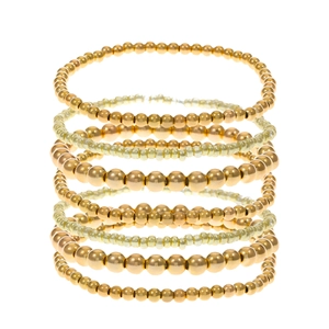 Dettaglio macro di bracciali a strati con perline dorate e finitura in metallo lucido