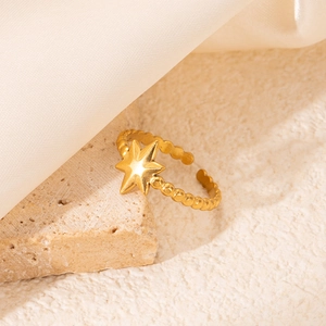 Gros plan d'une bague étoile en acier doré avec texture perlée et design ouvert