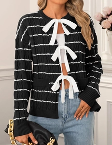 Detail of black striped cardigan featuring white bow tie closures and knitted texture