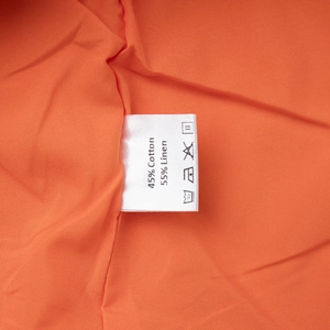 Detail of orange cotton-linen set showing wash care label with 55% linen and 45% cotton content
