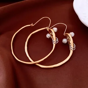 Chic gold-tone irregular hoop earrings with crystal ball pendants on silk background