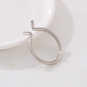 Minimalist silver stainless steel open ring displayed on white porcelain plate
