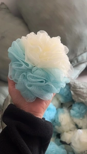 Close-up of a soft dual-tone mesh bath sponge in light blue and beige colors