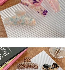 Detail view of large acetate hair claws in floral and tortoiseshell patterns on a tray