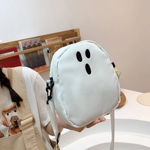 Détail d'un sac bandoulière blanc motif fantôme avec visage souriant porté par modèle