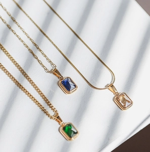 Vista dettagliata di collane placcate in oro 18K con gemme color smeraldo, blu e trasparenti