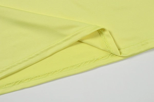 Détail de l'ourlet de robe en maille jaune clair avec couture plate à double aiguille