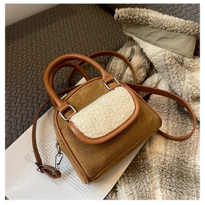 Detail of brown faux suede handbag with white plush trim and silver hardware accents