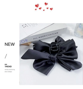 Detail of a large black satin bow hair claw clip with French vintage style and silk texture