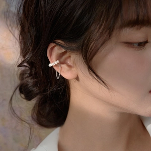 Detail view of a gold-plated pearl ear cuff with a fringe chain tassel on a model