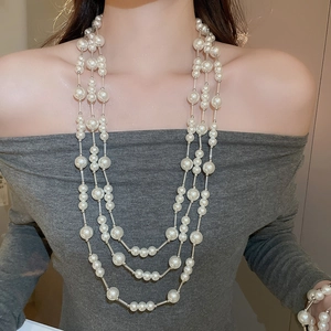 Detailed view of elegant triple-layer pearl necklace with silver chain on model