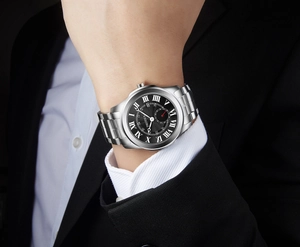 Close-up view of a silver men's watch with Roman numerals paired with a black business suit